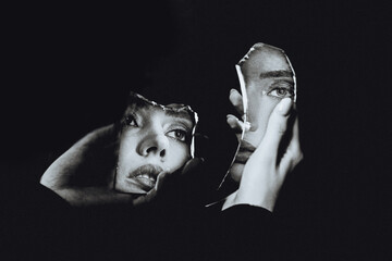 Young woman face reflected in brocken mirror, black and white portrait