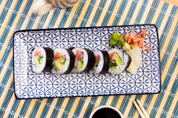 Traditional thick sushi roll futomaki filled with salmon, tuna, avocado, surimi and cucumber