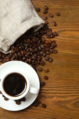 Cup of coffee with fresh coffee beans on wooden background