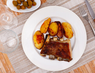 Delicious barbecued pork spare ribs served with baked potatoes on plate