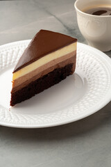 Delicious slice of chocolate mousse cake served on a white plate with a cup of coffee nearby