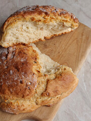 Homemade white bread on the wooden cutting board, lying on the marble table. Advert for bakery, cafe and restaurants. Vertical.