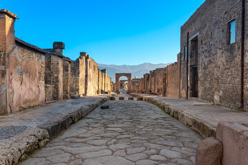 Via Di Mercurio in Pompeii is a main road known in ancient Rome as the cardo maximus. A north-south street that crosses the city. In the background, the Arch of Caligula