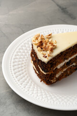 Delicious layered cake topped with cream and nuts placed on a white decorative plate