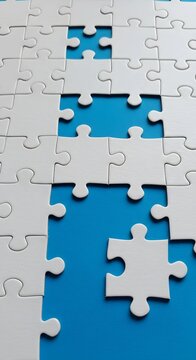 Close-up of incomplete white puzzle pieces on a blue surface, showcasing problem-solving, teamwork and the challenge of filling missing connections
