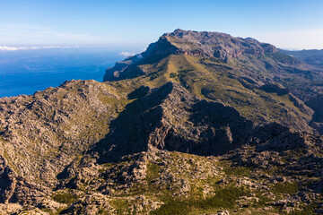 Stunning aerial view Tramuntana mountain range in Mallorca, with rugged peaks,deep blue Mediterranean Sea, soft clouds drifting above. Breathtaking natural landscape showcasing beauty island