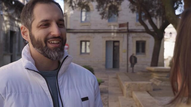 Cheerful bearded man talking to a friend in a city square