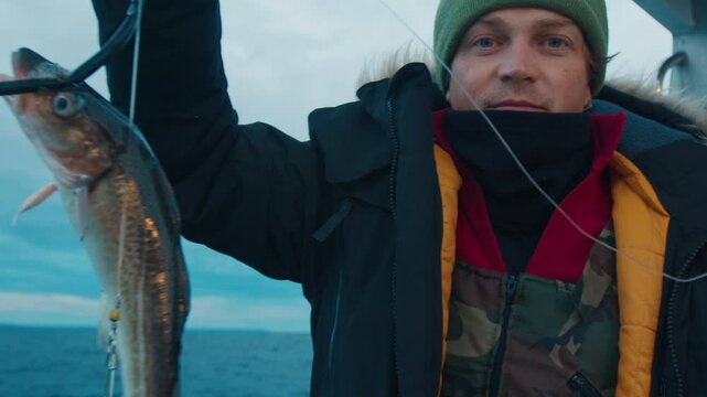 Fisherman shows his codfish catch on a fishing boat