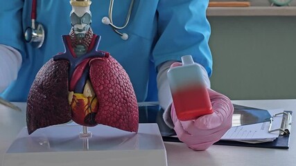 Doctor holds vape cigarettes and lung anatomy. Consequences of smoking electronic cigarettes vape
