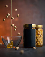 Glass jars with honey and hazelnuts. Nuts falling into honey. Natural sweetness on rustic wooden surface. Food concept, ready to eat, healthy eating sugar free. Snack, breakfast, dessert. Copy space.