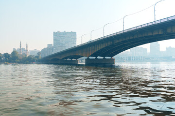 View of a bridge over water with city skyline in the background during a sunny day