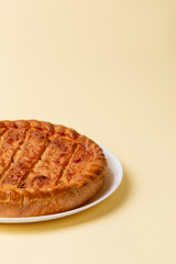 Tasty sweet pie on a white ceramic plate from above view on beige background.