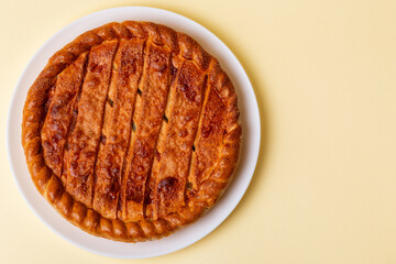 Tasty sweet pie on a white ceramic plate from above view on beige background.