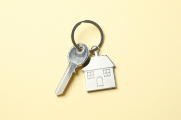 Metallic key with keychain in shape of house on color background