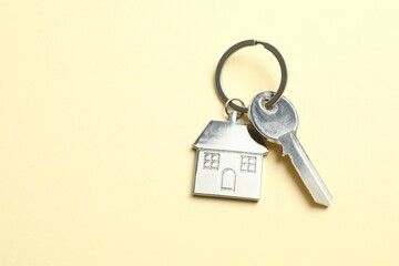 Metallic key with keychain in shape of house on color background