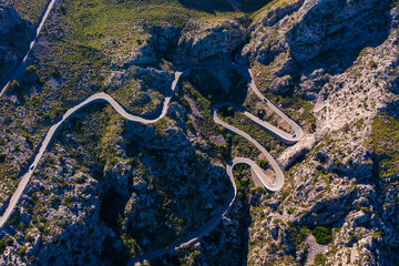 Stunning aerial shot iconic Sa Calobra road winding through Tramuntana Mountains in Mallorca. Serpentine mountain pass, with sharp curves- top destination for travelers and cycling enthusiasts.