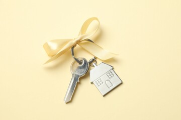 Metallic key with keychain in shape of house on color background