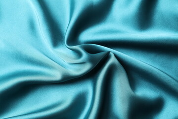 Silk satin dark turquoise color. Shiny smooth fabric. Soft folds. Luxury background with space for design. Flat table, top view