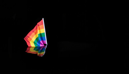 Rainbow flag reflected on dark water, symbolic representation of LGBTQ+ pride and resilience