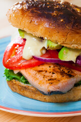 Appetizing vegetarian burger with roasted fillet of trout, ripe avocado, fresh lettuce, tomatoes