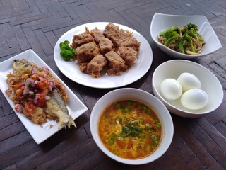 spicy fried fish, fried tofu and boiled egg on wooden table