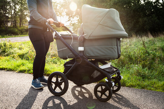 Low section of woman holding baby stroller on road