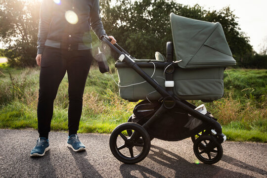 Low section of mother holding baby stroller on road