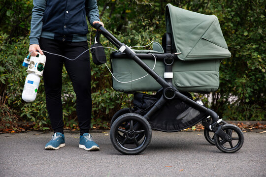 Low section of woman holding oxygen tank attached with baby stroller