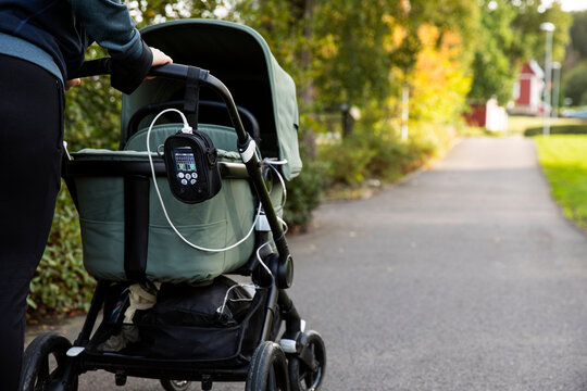 Midsection of woman holding baby stroller with medical equipment