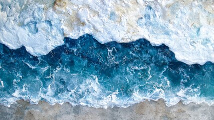 Aerial View of Turquoise Ocean Waves Crashing Against Sandy Shoreline with White Foam and Clear Water Details