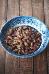 Pistachios in a decorative bowl on a wooden table