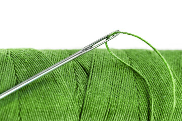 Old Single wooden spool of thread closeup light green color and needle white background