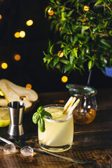 Refreshing pear and basil cocktail garnished with lemongrass on rustic wooden table