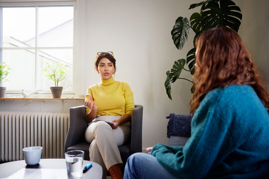 Female psychotherapist talking with young woman at office