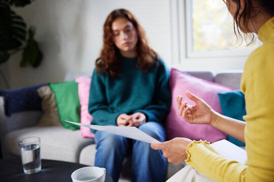 Midsection of female psychotherapist discussing medical reports with depressed woman during therapy session