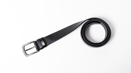 Black leather belt with matte metal buckle close-up isolated on white background. Fashionable everyday unisex accessory for jeans. Stylish mens or womens strap. Haberdashery goods. Empty text space.