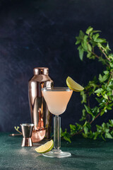 Pink cocktail being poured into elegant glass with copper shaker and jigger