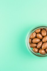 Glass jar filled with smooth chocolate-covered almonds on mint b