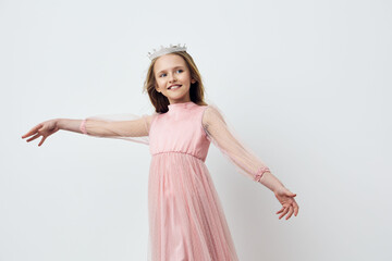 Naklejka premium Happy girl in a pink dress with a crown, twirling joyfully against a clean white background, perfect for celebrating childhood and special occasions