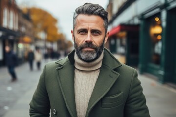 Naklejka premium Portrait of a handsome bearded man in a green coat on a city street.