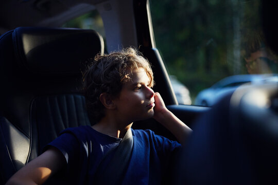 Contemplative boy sitting in car while looking through window on road trip