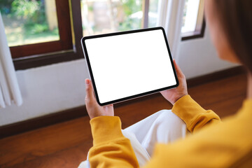 Mockup image of a woman holding tablet with blank desktop white screen at home