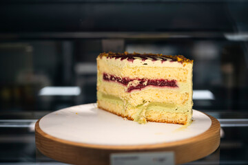 A slice of sponge cake with pistachio ganache and raspberry coulis.