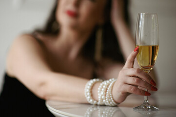 A woman elegantly holds a glass of champagne, capturing a moment of celebration and sophistication. The sparkling bubbles and delicate grip create a refined and festive atmosphere.