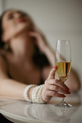 A woman elegantly holds a glass of champagne, capturing a moment of celebration and sophistication. The sparkling bubbles and delicate grip create a refined and festive atmosphere.