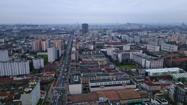 Aerial drone sideways over Aubervilliers densely inhabited city with buildings and streets. Tour Eiffel and La D&eacute;fense in background. Paris region, Seine Saint-Denis in France.