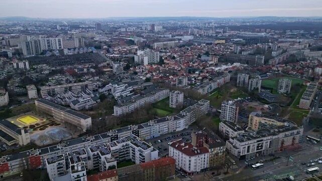Panorama drone view of Paris skyline with sprawling cityscape and cloudy sky, France.
