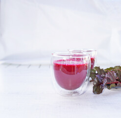 A cup of fresh beetroot juice with leaves on table.