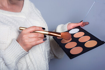 A palette of blush in the hands of a make-up artist close-up.