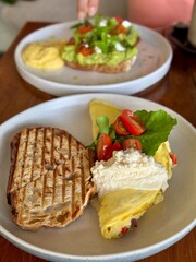 Breakfast with scrambled eggs, toast, sausage, cherry tomatoes, lettuce and avocado on a white plate